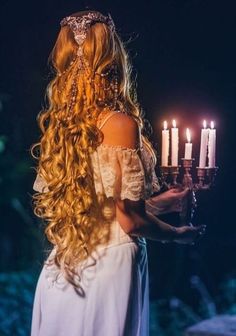 a woman with long hair holding candles in her hand