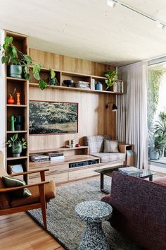 a living room filled with furniture and lots of plants on top of it's shelves