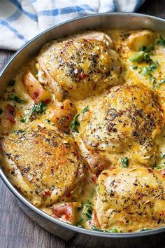 a pan filled with chicken and vegetables on top of a wooden table