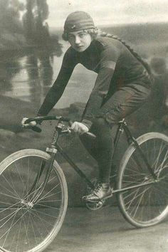 an old black and white photo of a woman riding a bike in the early 20th century