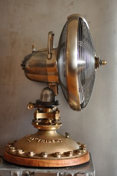 an old fashioned steam engine lamp on top of a metal stand with wheels and knobs