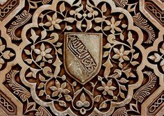 an intricately carved wooden panel with a shield on it's center, surrounded by flowers and leaves