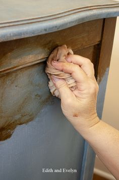 a person is holding something in their hand on top of a table that has been painted blue