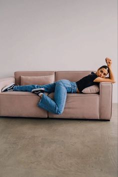 a woman laying on top of a couch with her arms in the air