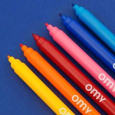 four different colored crayon pens sitting next to each other on a blue surface