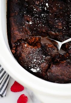 a close up of a spoon in a bowl filled with pudding and topped with powdered sugar