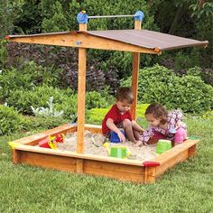 two children playing in a sandbox on the grass