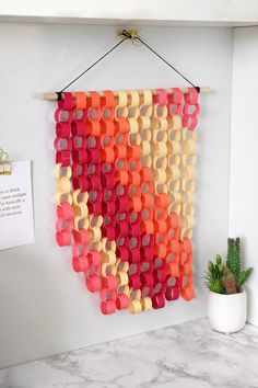 a wall hanging made out of orange, pink and yellow circles on a white wall