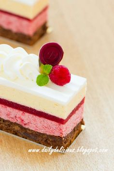 three desserts are sitting on a table with white frosting and raspberries