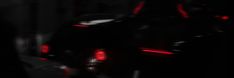 the tail lights of a black car are glowing red in the dark night time scene