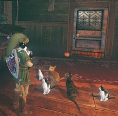 a man standing next to two cats on top of a wooden floor in front of another cat