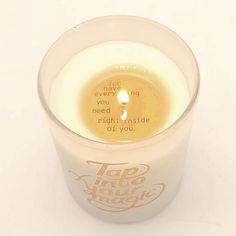 a candle that is inside of a cup with some writing on the top and bottom