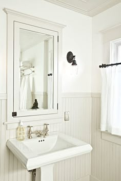 a white sink sitting under a bathroom mirror