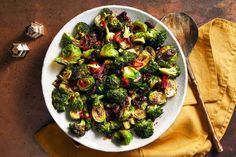 a white bowl filled with broccoli and cranberries on top of a yellow napkin