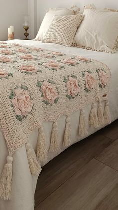 a white bed with pink flowers and tassels on it