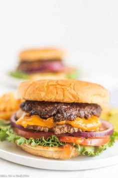 a hamburger on a plate with onion, cheese and lettuce