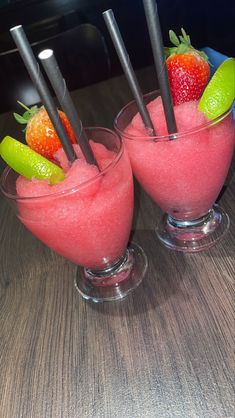 two glasses filled with fruit on top of a wooden table