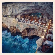 an outdoor dining area next to the ocean with tables and chairs set up on the cliff