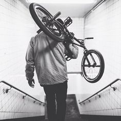 a man carrying a bicycle up an escalator with his back to the camera