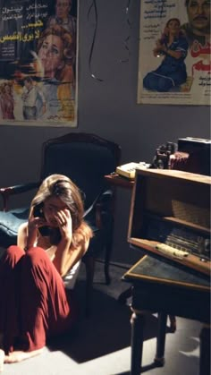 a woman is sitting on the floor talking on her cell phone and looking at pictures