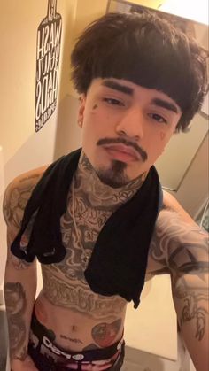 a man with tattoos on his chest and scarf around his neck is taking a selfie