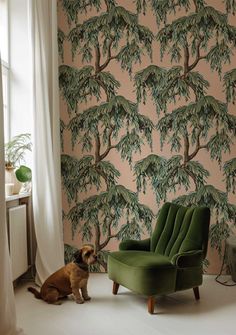 a green chair sitting in front of a wall with a tree mural on it's side