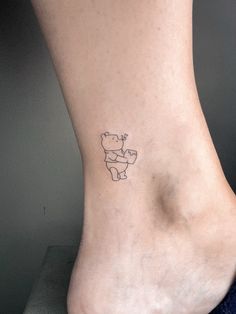 a small bear tattoo on the ankle