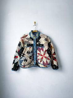 a jacket hanging on a white wall with a black and red pattern in the middle