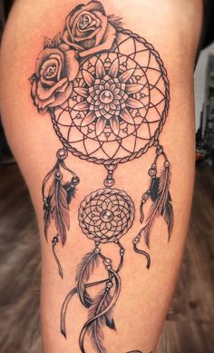 a woman's thigh with a black and white dream catcher tattoo on her leg