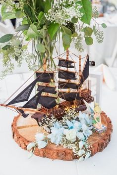 a vase filled with flowers sitting on top of a wooden table next to a boat