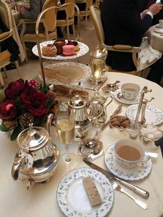 a table topped with plates and cups filled with desserts next to silverware on top of tables