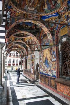 a man is standing in the middle of a building with many paintings on it's walls