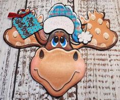 a moose with a hat and scarf hanging from it's side on a wooden surface