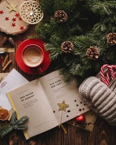 an open book on top of a wooden table next to christmas decorations and other items