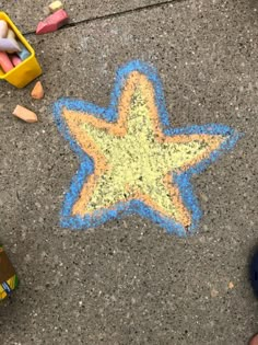 a child's chalk drawing of a star on the ground next to crayons