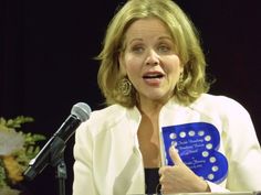 a woman giving a speech at a podium with a blue plaque in front of her