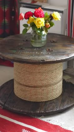 a vase with flowers sitting on top of a wooden table next to a red and white striped rug