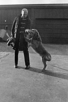 an old black and white photo of a man playing with a dog