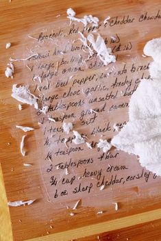 a piece of paper with writing on it sitting on top of a wooden cutting board