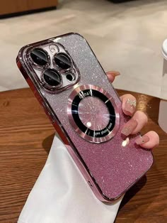 a woman's hand holding a pink glitter phone case