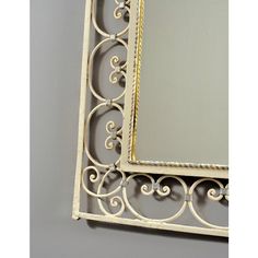 an ornate white metal frame mirror on a gray wall