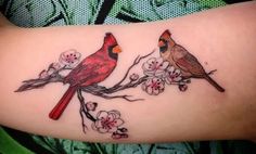 two birds sitting on a branch with flowers