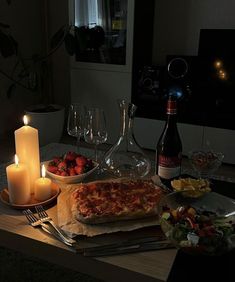 a table topped with pizza and plates of food next to candles on top of it