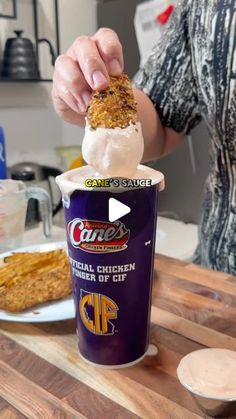 a person is dipping some kind of food into an ice cream cup on a wooden table