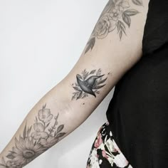 a woman's arm with flowers and a bird tattoo on the left side of her arm