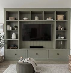 a living room filled with furniture and a flat screen tv on top of a wooden shelf