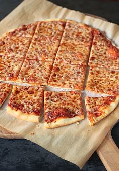 a sliced pizza sitting on top of a wooden cutting board next to a spatula