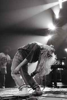 a woman standing on top of a stage next to a piano