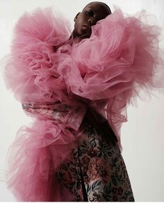 a woman in a pink dress with large ruffles on her head and arms