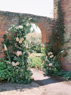 an arch in the wall with flowers growing out of it and greenery around it